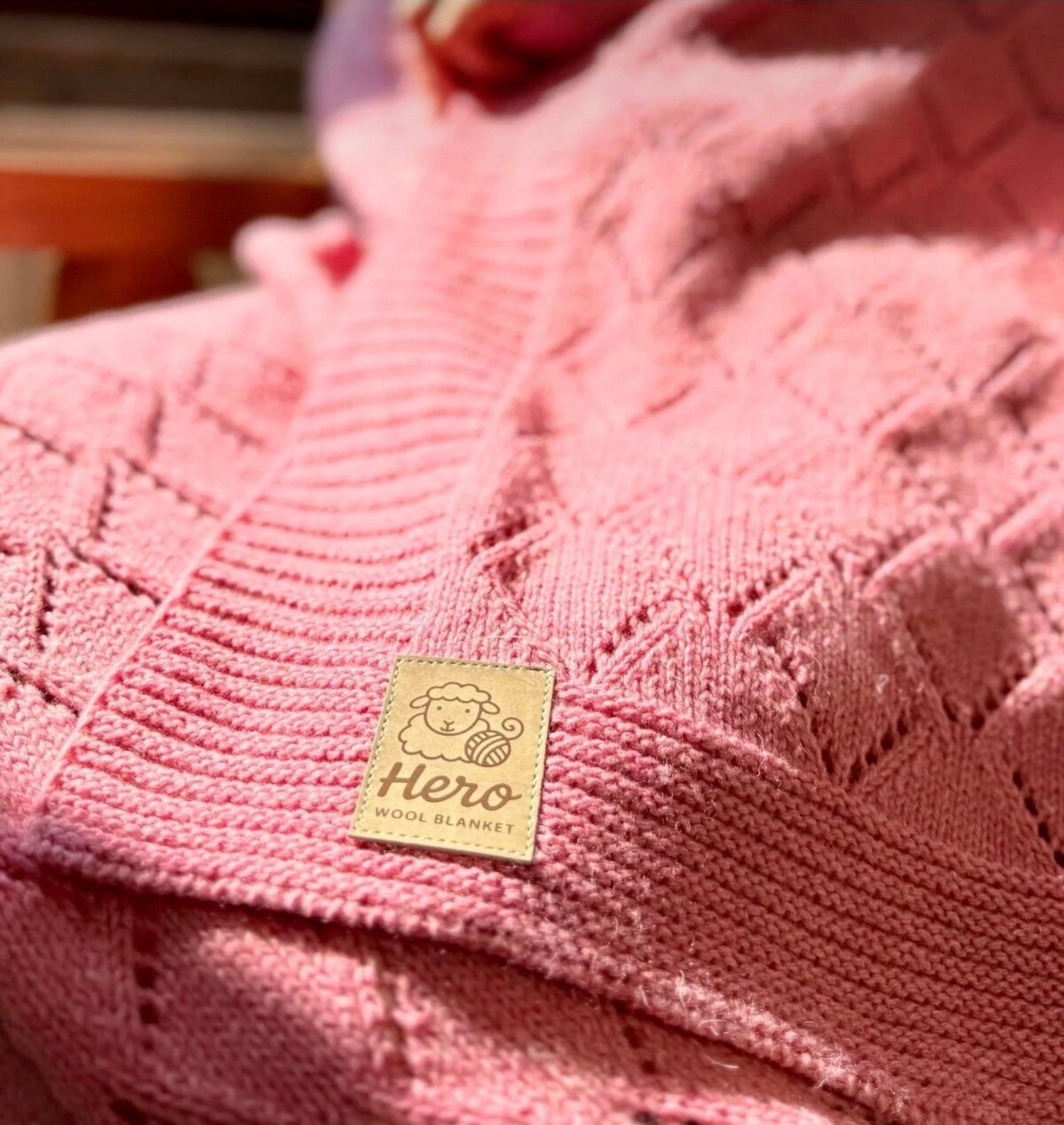 Close-up of a pink knitted blanket with a 'Hero' label on it.