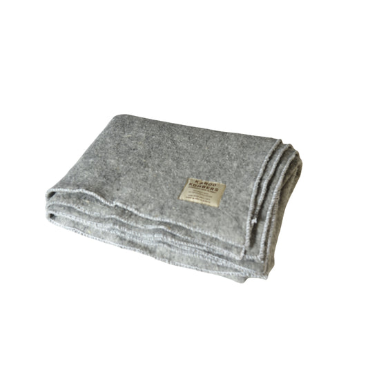 A folded gray wool blanket with a small beige label, shown on a plain white background.
