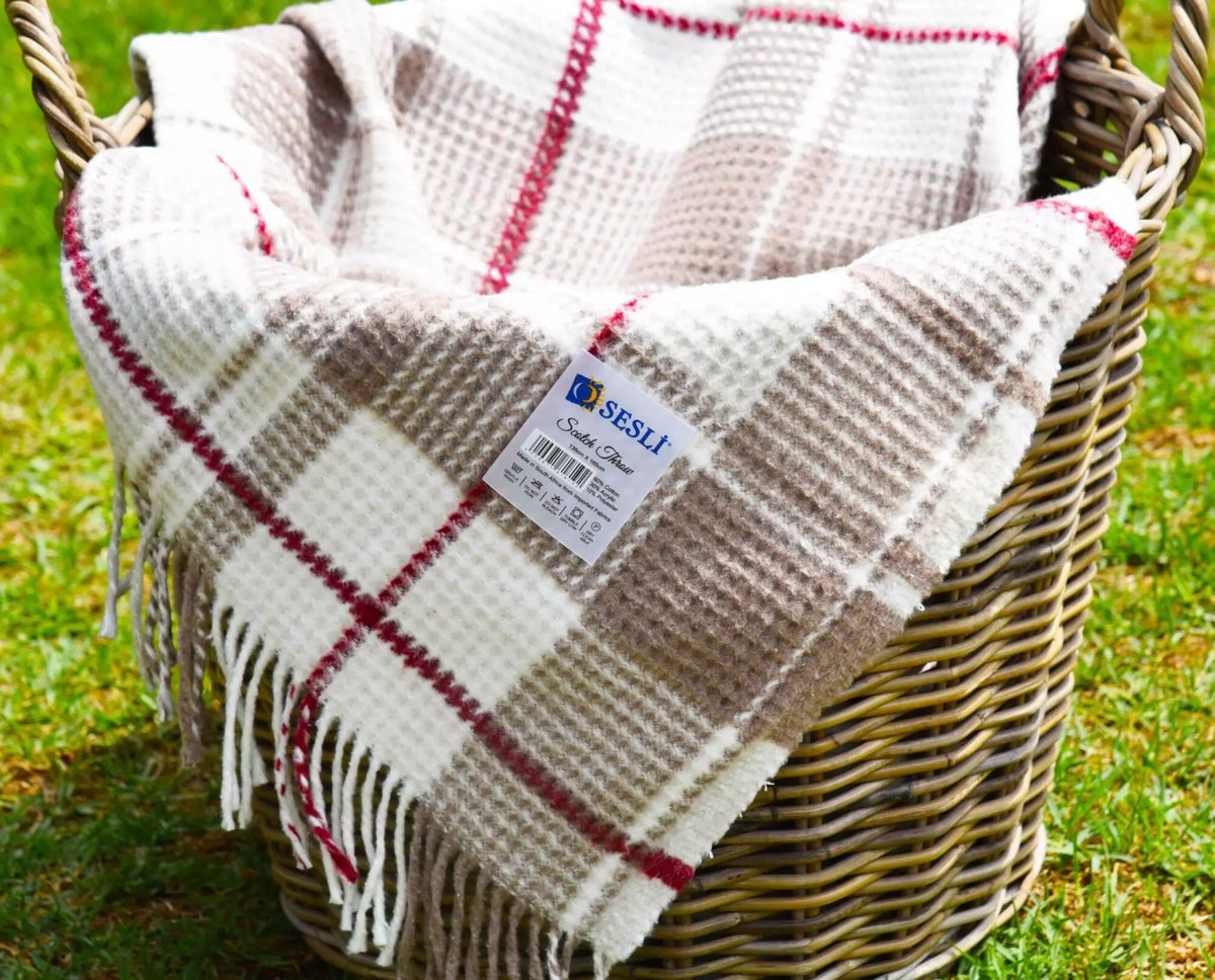 Plaid blanket with fringes in a wicker basket on grass