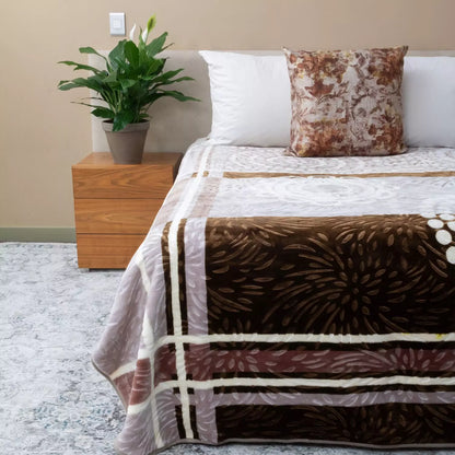 Bed with brown and white patterned blanket, white pillows, and a wooden nightstand with a plant.